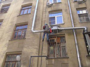 un alpinist montează o unitate de ventilație în afara clădirii
